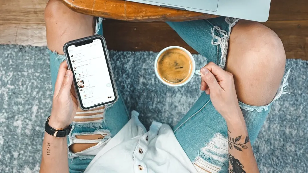 Smartphone in mano e tazza di caffè