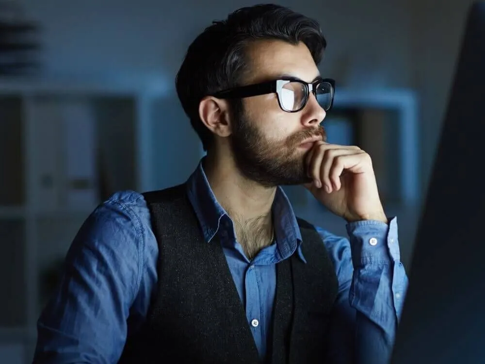 Professionista concentrato davanti al monitor in un ufficio in penombra